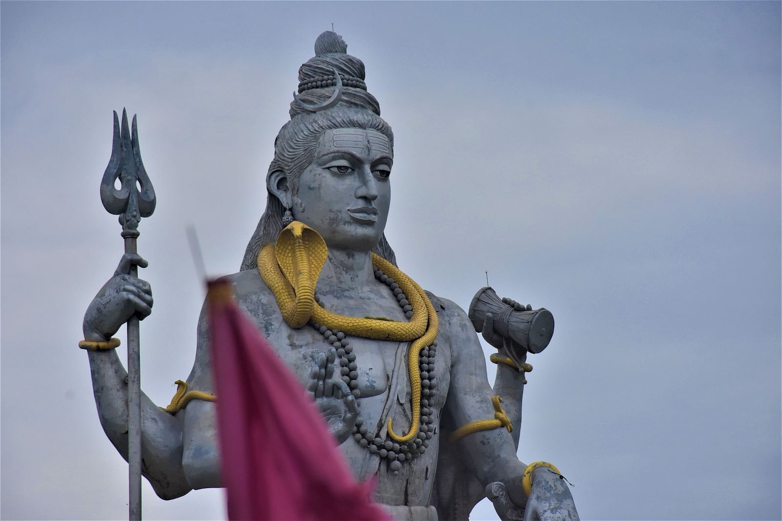 Close-up of a stone statue of Lord Shiva draped in red fabric- Kumarakom 