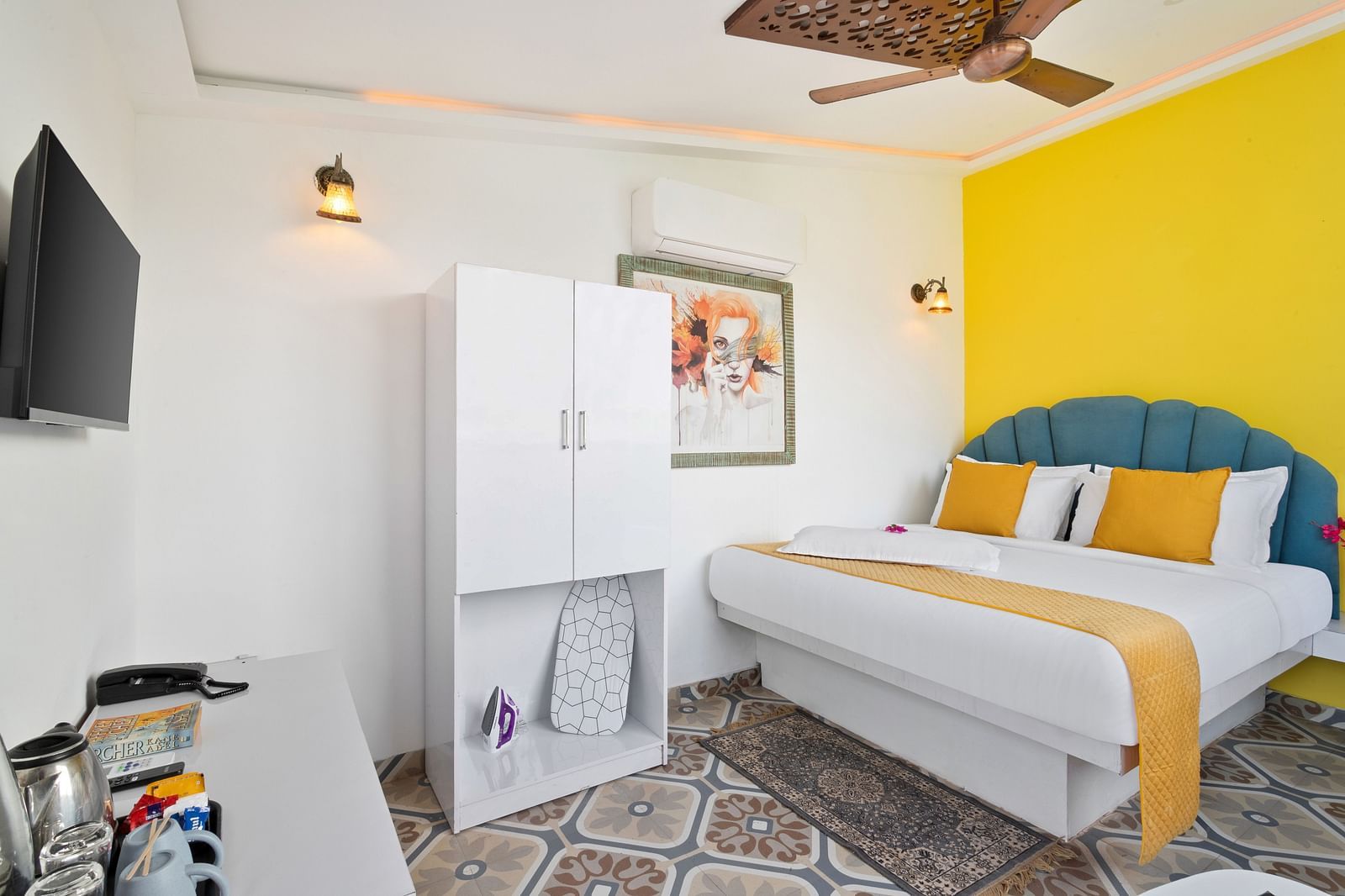 A stylish bedroom with a white wardrobe, yellow accents, and a television mounted on the wall.