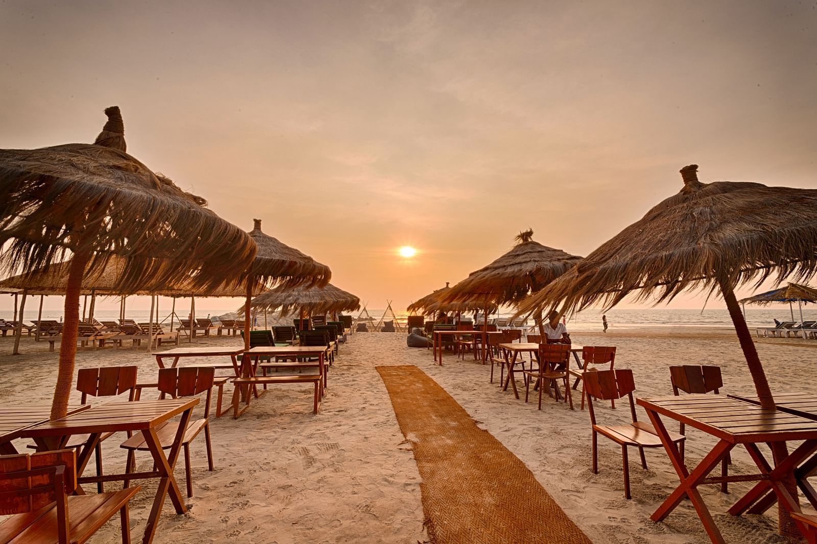 Sunset dining setup with beach chairs and umbrellas at Royale Amata by the Beach Restaurant