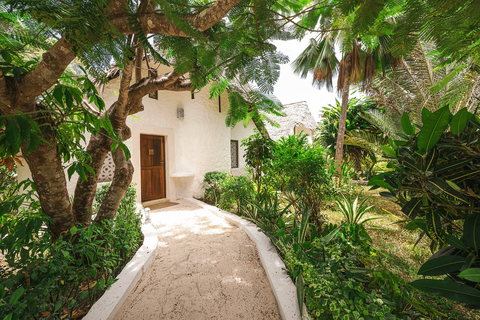 Tropical garden pathway leading to a private villa, surrounded by lush greenery - Shooting Star Boutique Hotel.