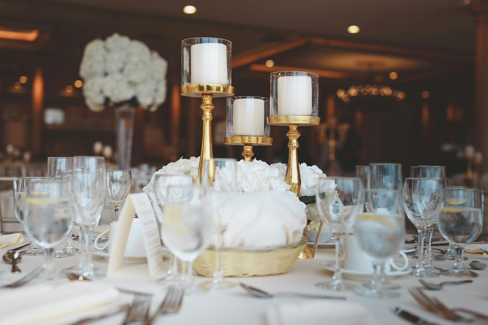 Elegantly set table with glassware, candlesticks and a white decorative object.