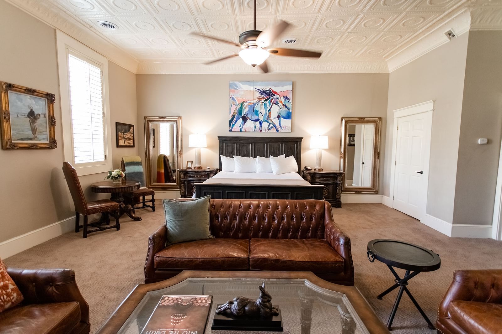 Suite with bed, leather sofa, chairs, and ceiling fan at The Grand Hotel & Ballroom, McKinney.