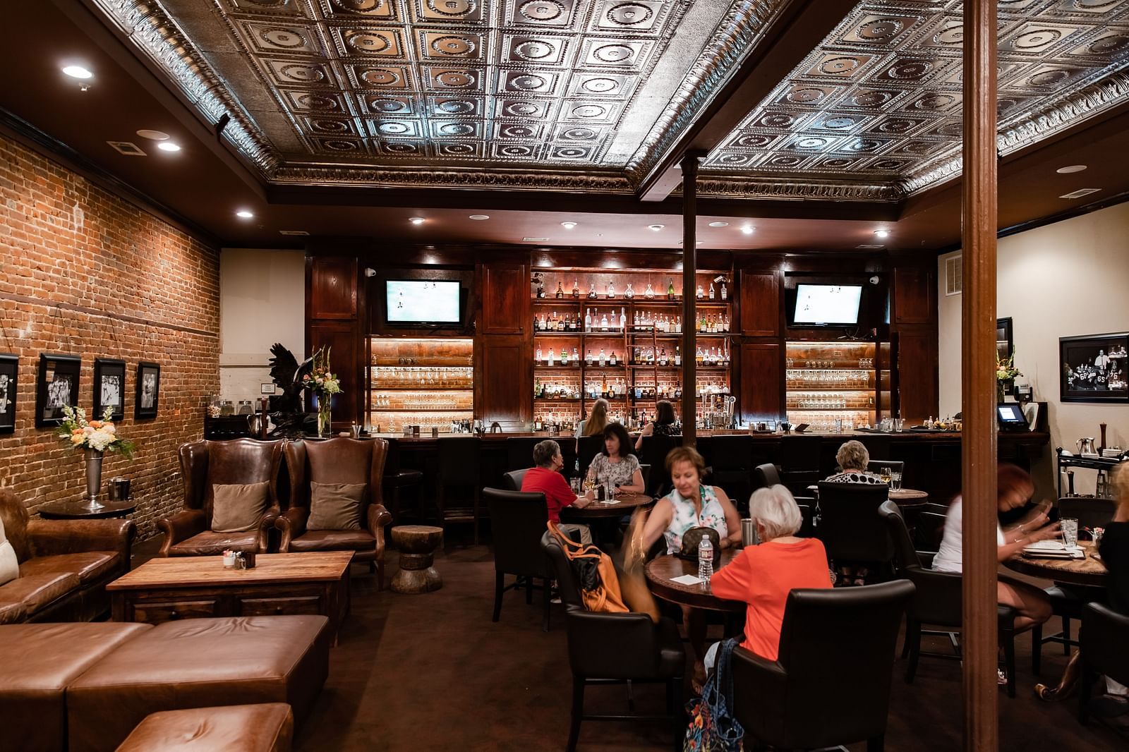 A spacious restaurant interior with tables, booths, high ceilings, and a large bookshelf along one wall.- The Grand Hotel & Ballroom, McKinney