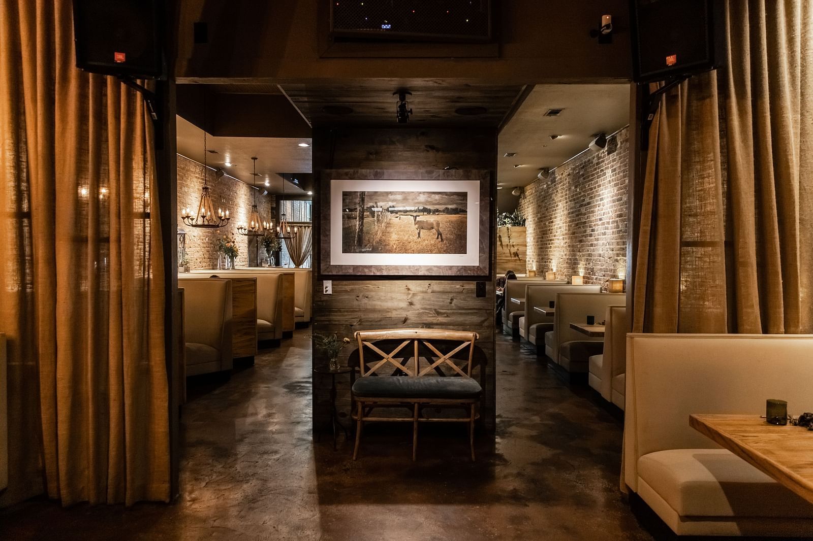 A dimly lit private dining space with booth seating, elegant drapes, and a framed artwork at the far end.- The Grand Hotel & Ballroom, McKinney