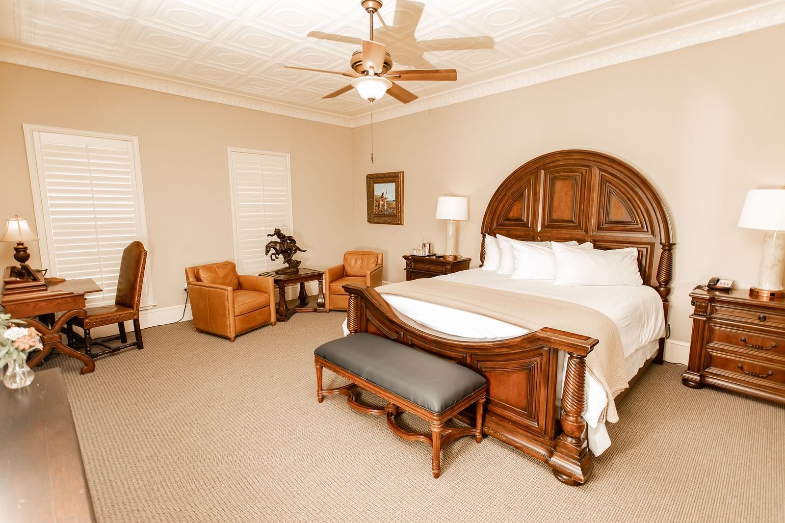 Bedroom with wooden bed and leather seating at The Grand Hotel & Ballroom, McKinney.