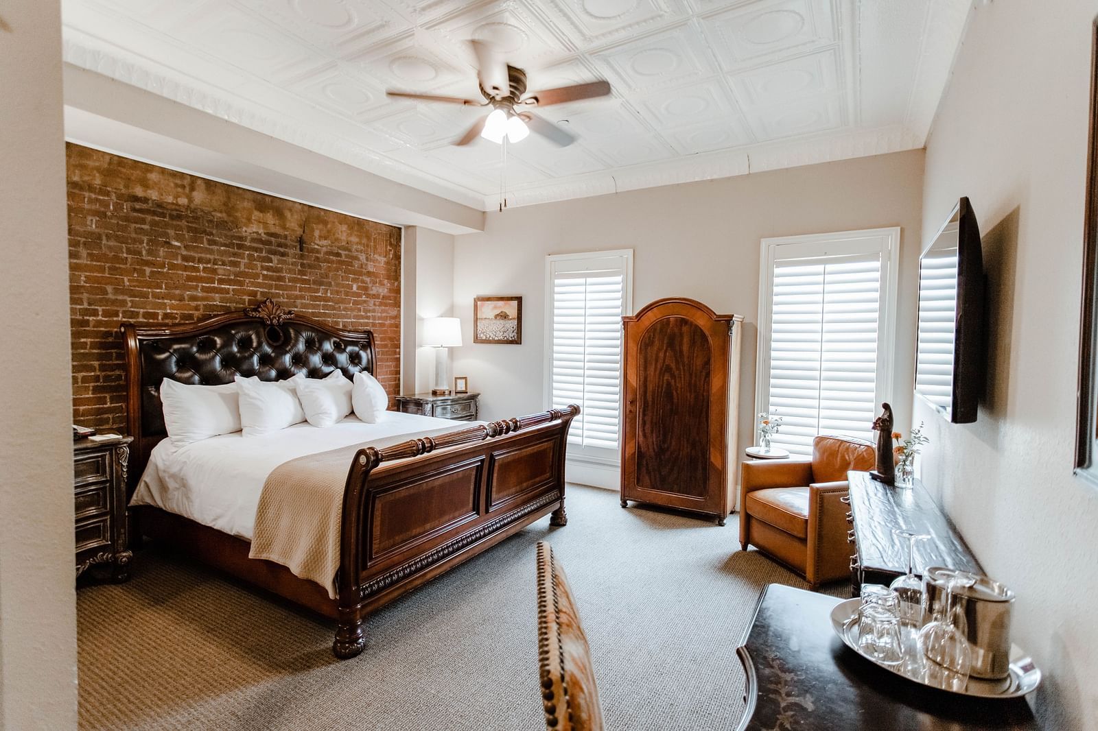 A spacious bedroom with a leather chair, modern decor, and a large bed, creating a stylish and comfortable living space - The Grand Hotel & Ballroom, McKinney