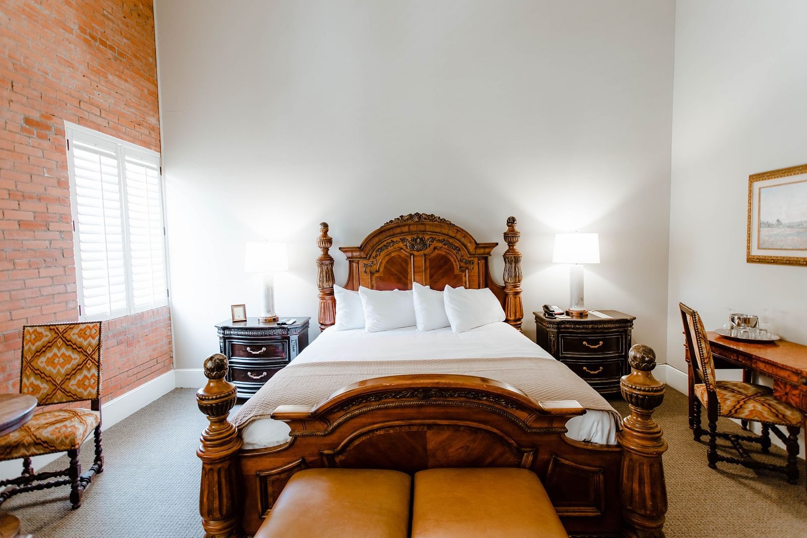 A stylish bedroom featuring a large wooden bed, soft lighting, and elegant decor, creating a relaxing and warm atmosphere - The Grand Hotel & Ballroom, McKinney