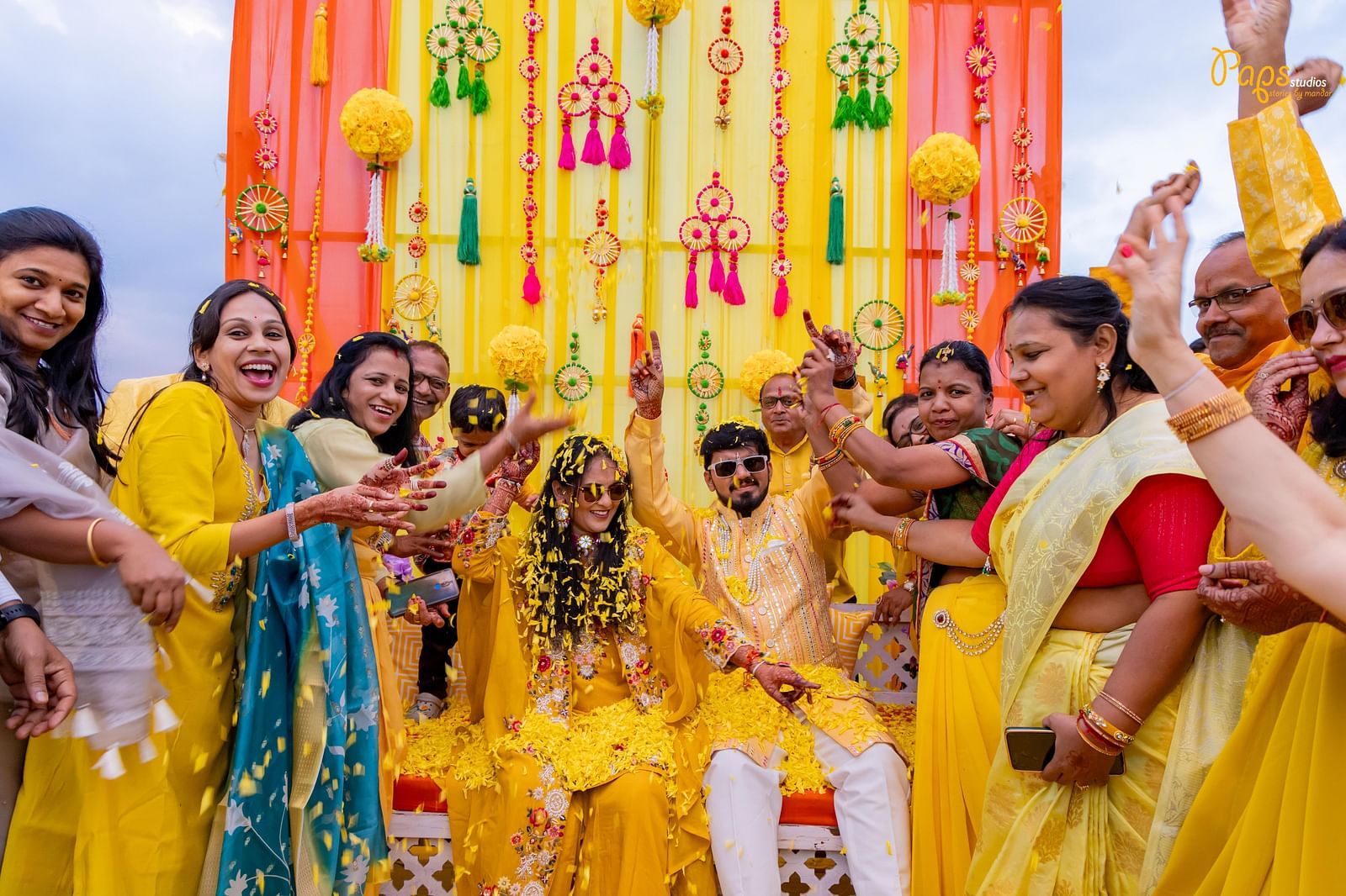 Joyful women in sarees dance under colourful decorations, celebrating with raised hands in what appears to be a festive gathering - The Grand Legacy Resort and Spa