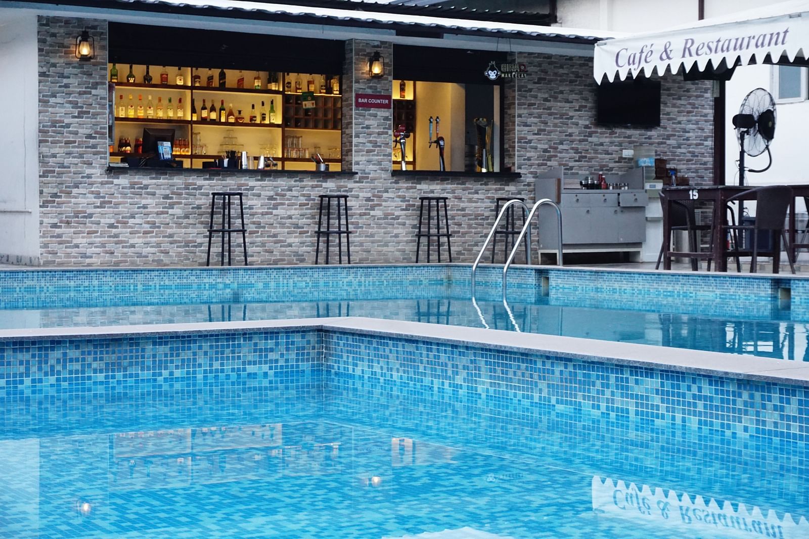 Bar next to pool under evening sky. | Vistar Resort, Bengaluru