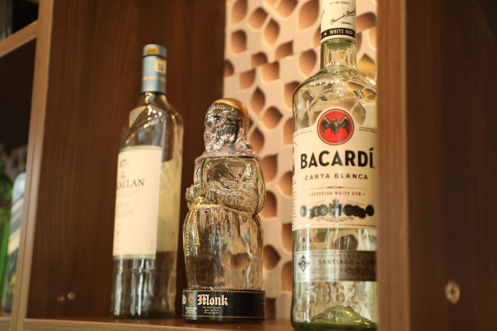 Alcohol bottles placed on brown wooden shelf - Welcome Inn Hotels