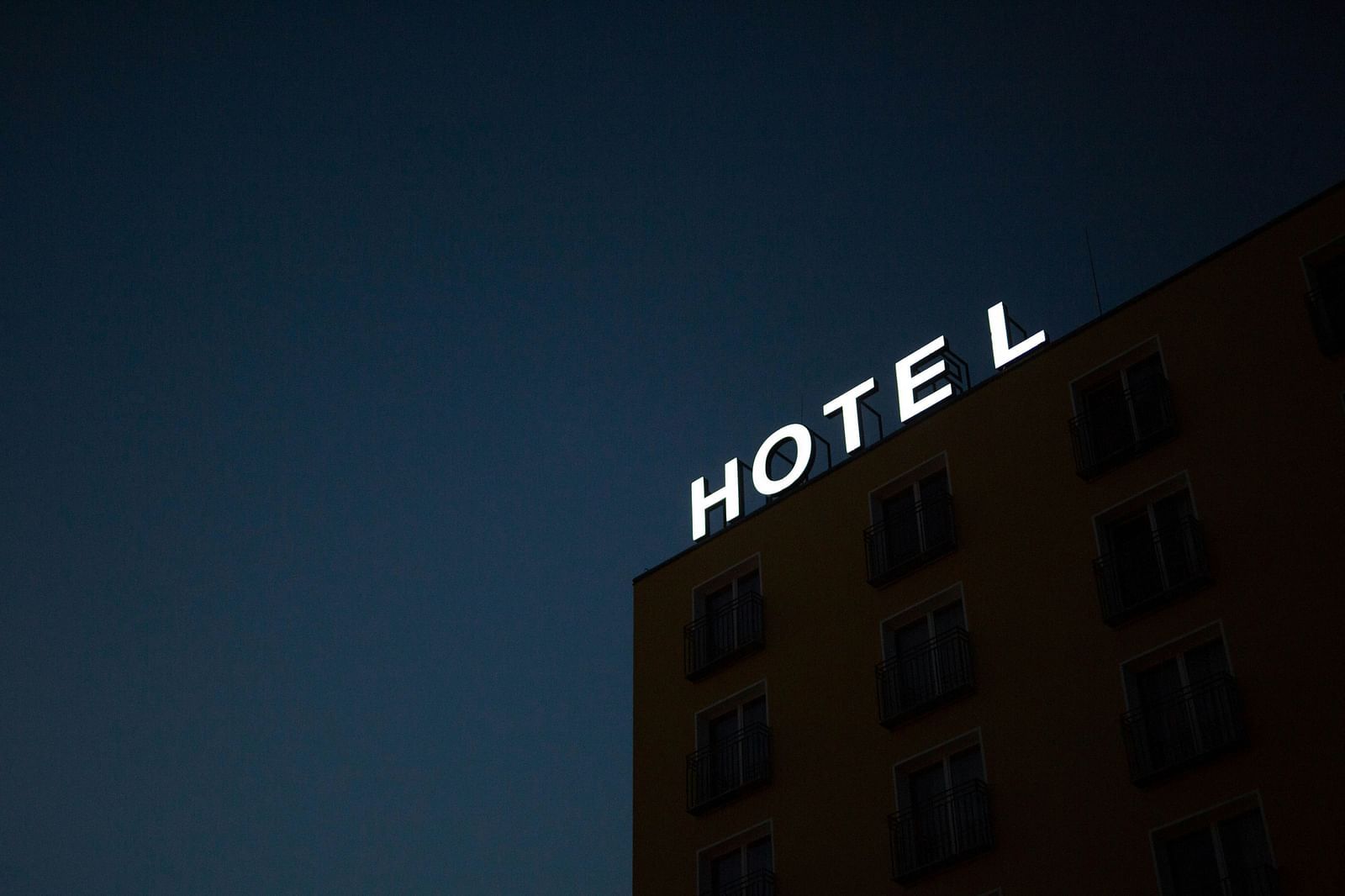 A night time view of a building with an illuminated sign board on top of it