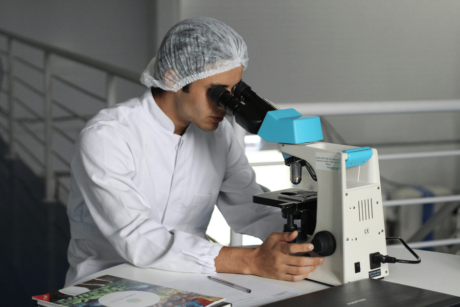 A medical personnel inspecting a specimen through a microscope
