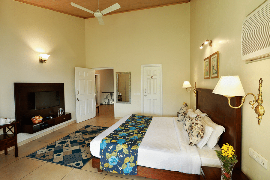 An elegant room with pristine white bed and delicate interiors, captured from a lower angle showing room amenities like  television, bedside lamp and more - Lamrin Norwood Green, Palampur