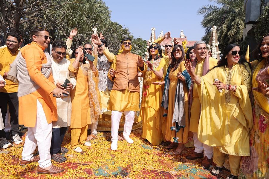 alt-text Bride and groom posing joyfully with friends during wedding celebrations at Shri Radha Brij Vasundhara Resort & Spa.
