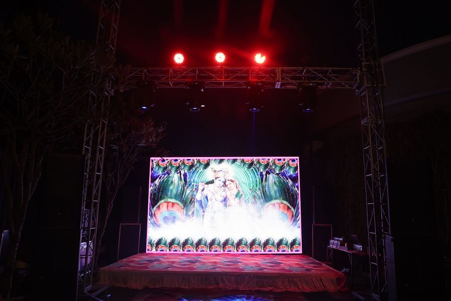 alt-text Beautifully illuminated anniversary decor with floral arrangements at Shri Radha Brij Vasundhara Resort & Spa.