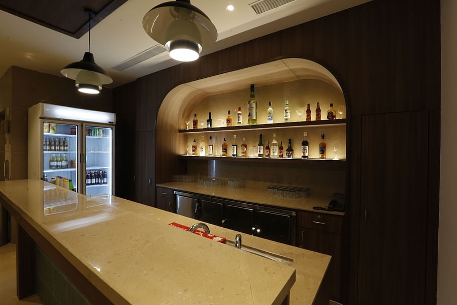 An image of bar counter featuring various liquor bottles placed on shelves and refrigerator - Tulip Inn, Zirakpur