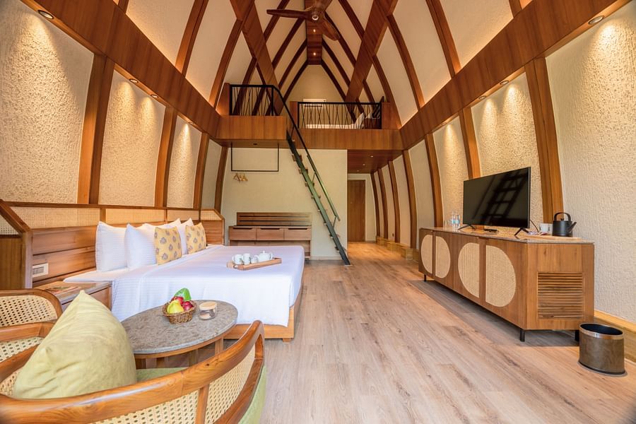 An image of attic style bedroom with a king size bed, a wooden seating area, a flat TV screen, a table counter top, and a  step ladder to reach the attic - Ananta Spa and Resort, Ajabgarh