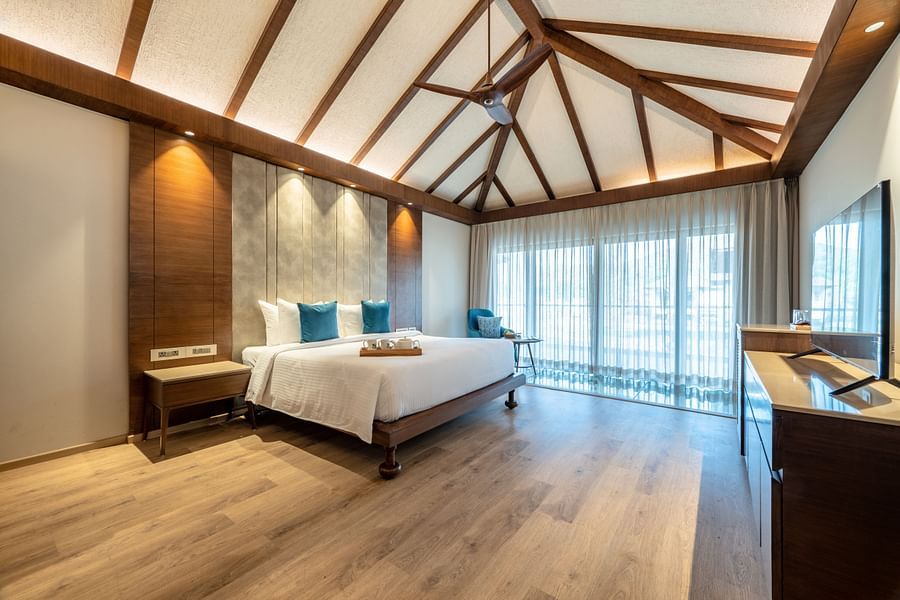 An image of a bedroom with double size bed, a bedside table, flat TV screen, a huge windows from where sunlight is flooding into the room - Ananta Spa and Resort, Ajabgarh