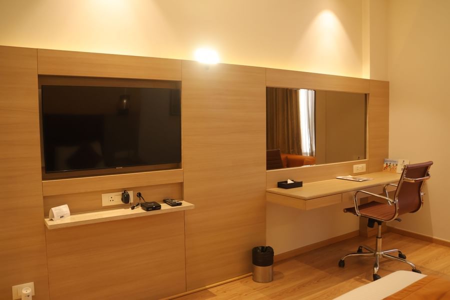 Hotel room workspace featuring flat screen TV, wooden desk, office chair and storage shelves at Best Western, Vrindavan.