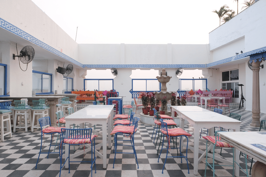 Open-air courtyard dining area featuring colourful seating, tiled flooring, a central fountain, and casual dining spaces designed for relaxed gatherings | Clarks Amer, Jaipur