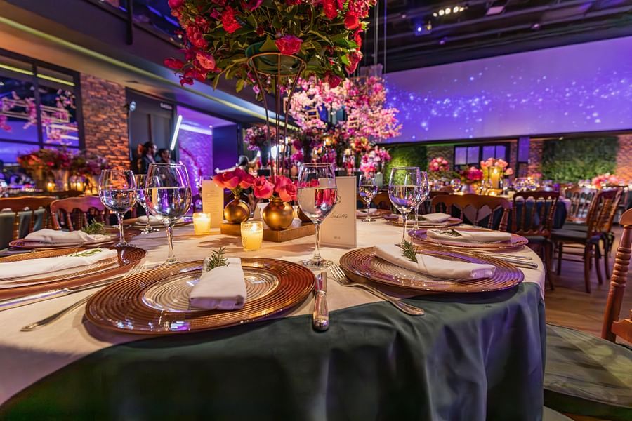 A large, ornate dinner table with colourful floral arrangements and candles, set in a beautifully decorated room