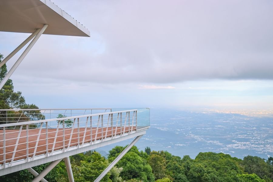 View of a balcony overlooking a lush valley and distant mountains at Ibex Resorts, Coonoor (Tapas).