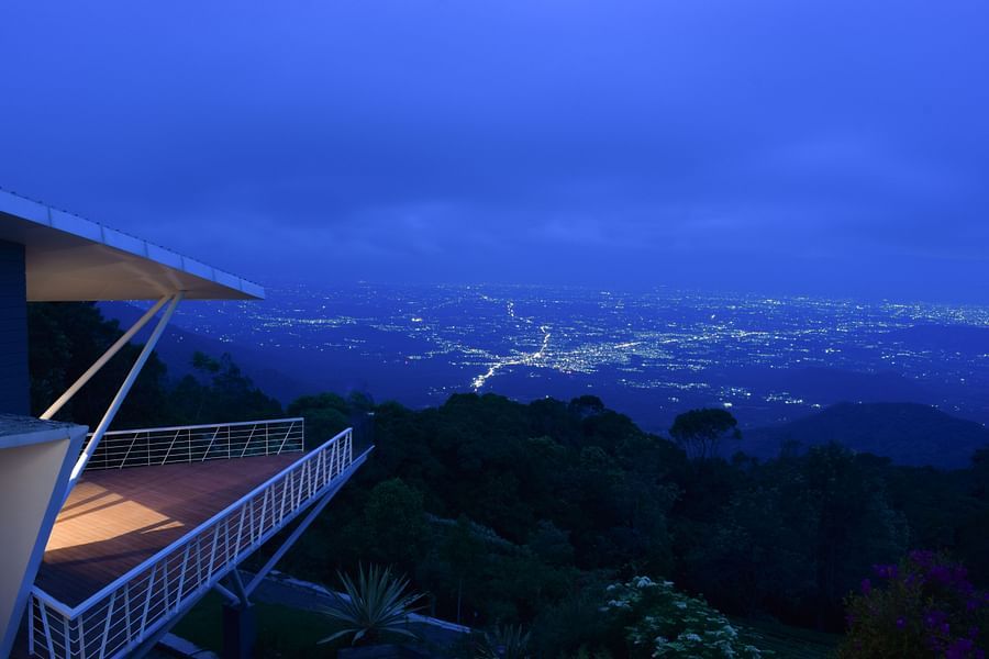 Twilight view of a balcony overlooking a lush valley and distant mountains at Ibex Resorts, Coonoor (Tapas).