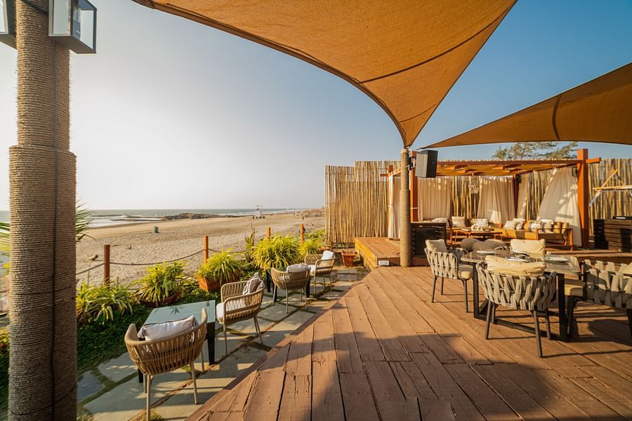 alt-text image of a restaurant situated next to the beach designed with wooden interior with posh decor