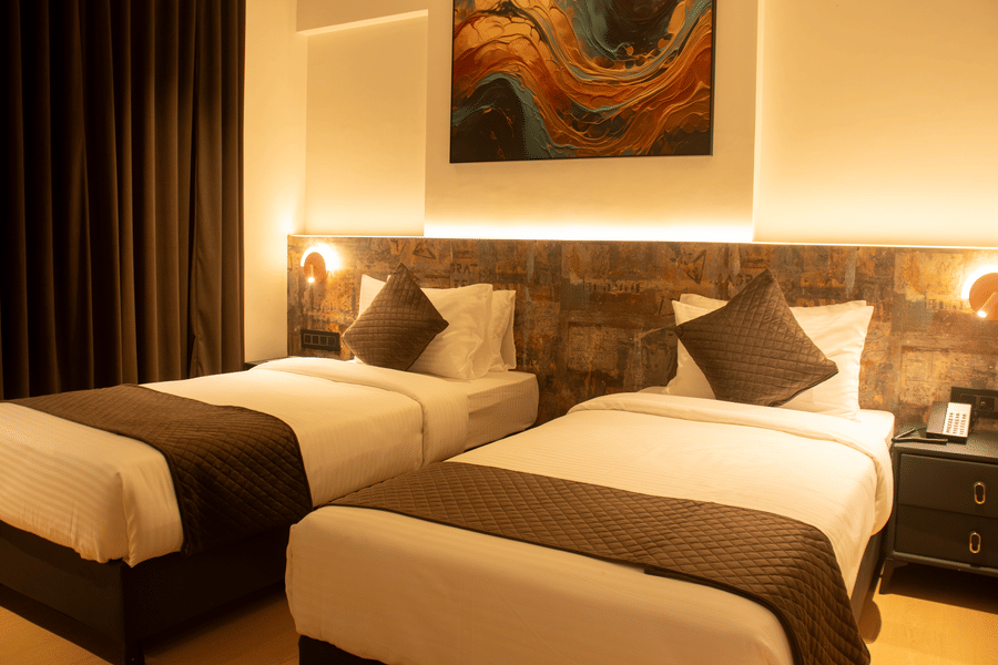 2 single beds room with bedside lamps, headboard panel, and wall art at Magnus Lxia Premier, Kalyani Nagar.