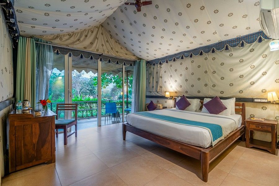 alt-text A luxurious bedroom with a canopy ceiling, patterned walls, and a scenic view through large windows.