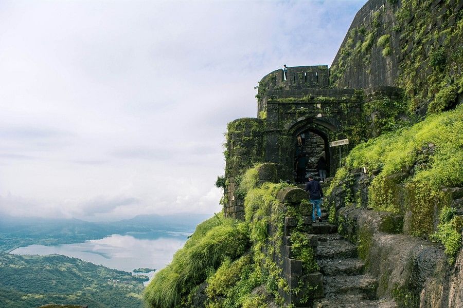 alt-text Ancient stone steps and archways covered with green moss on a foggy mountain, evoking a sense of mystery and historical depth in a natural setting.