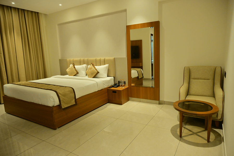 Bedroom of Bhavanis Vista By Icon featuring a bed, a headboard, an armchair, and a mirror.