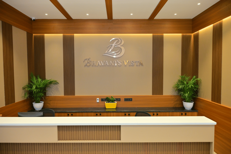 Reception desk of Bhavanis Vista By Icon featuring a counter, signage, and potted plants.