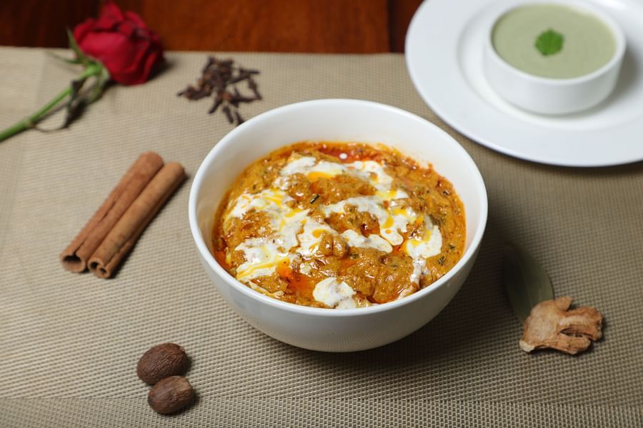 An image of a dish served in a bowl with a sauce and beside it there are cinnamon and rose at  a restaurant at Five Elements Hotel, Jodhpur 