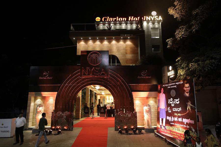 alt-text Night view of Clarion Bangalore, featuring a grand entrance with a red carpet, a decorative arch, and a promotional banner for an event.
