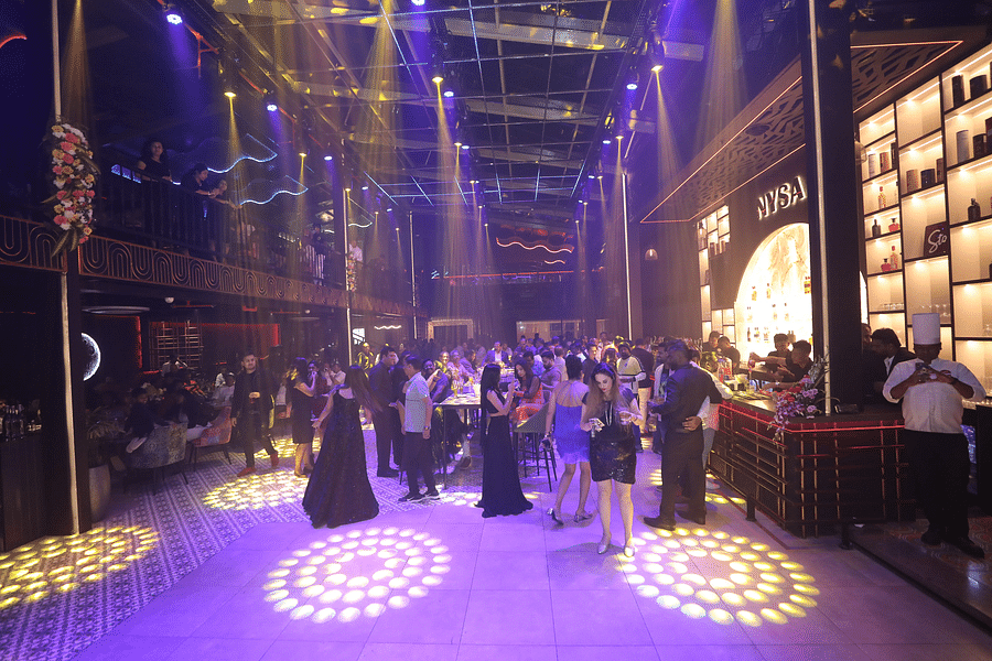 alt-text Vibrant party scene at Nysa Skybar with guests mingling and dancing under colourful lights, showcasing a lively atmosphere filled with energy and excitement.