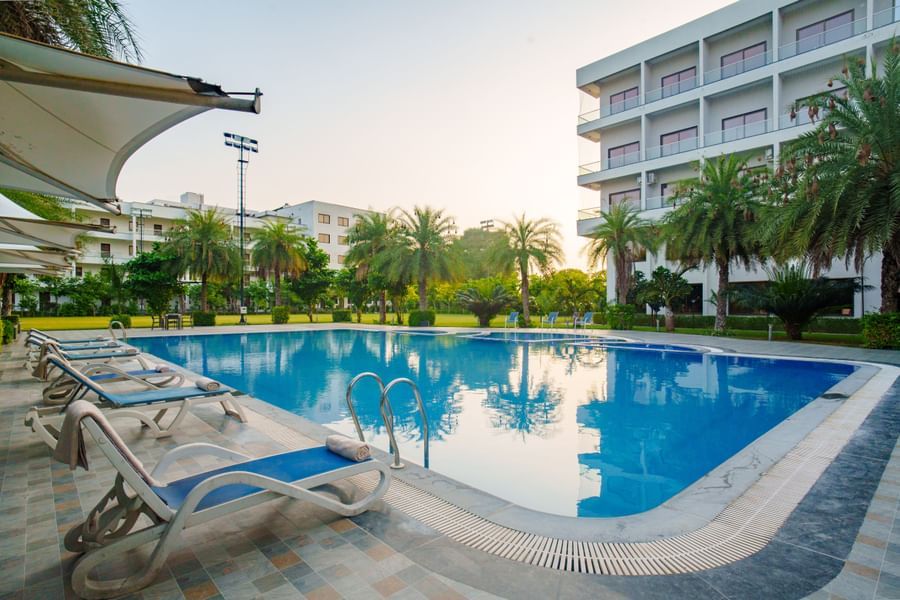 Swimming pool area with the hotel building visible in the background at Arawali Ananta Elite, Jaipur.