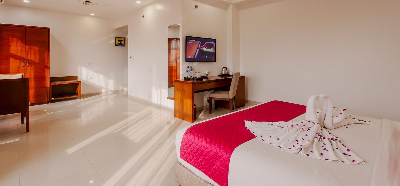 Spacious hotel room at Diamond Palace Lords Plaza featuring a double bed with colorful accents and a dedicated work area.