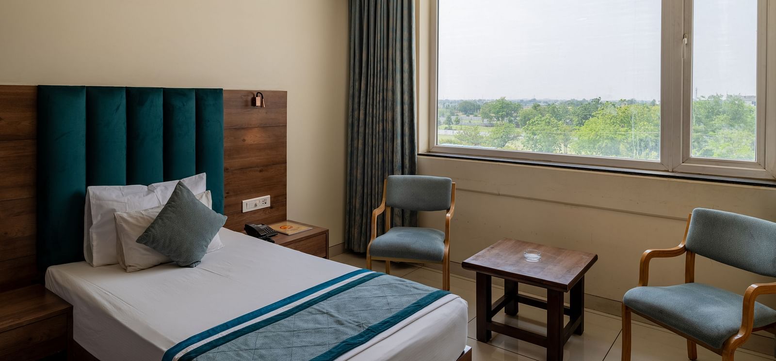 Lounge seating by the window with natural light in a King Twin bed Room at Hotel Highway King, Bilaspur.