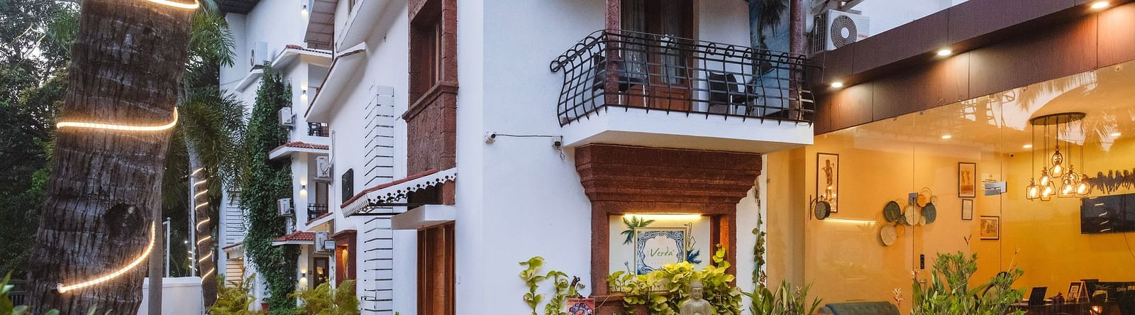 Exterior facade of the resort buildings with a tiled walkway and palm trees at The Verda de Miranda Resort.