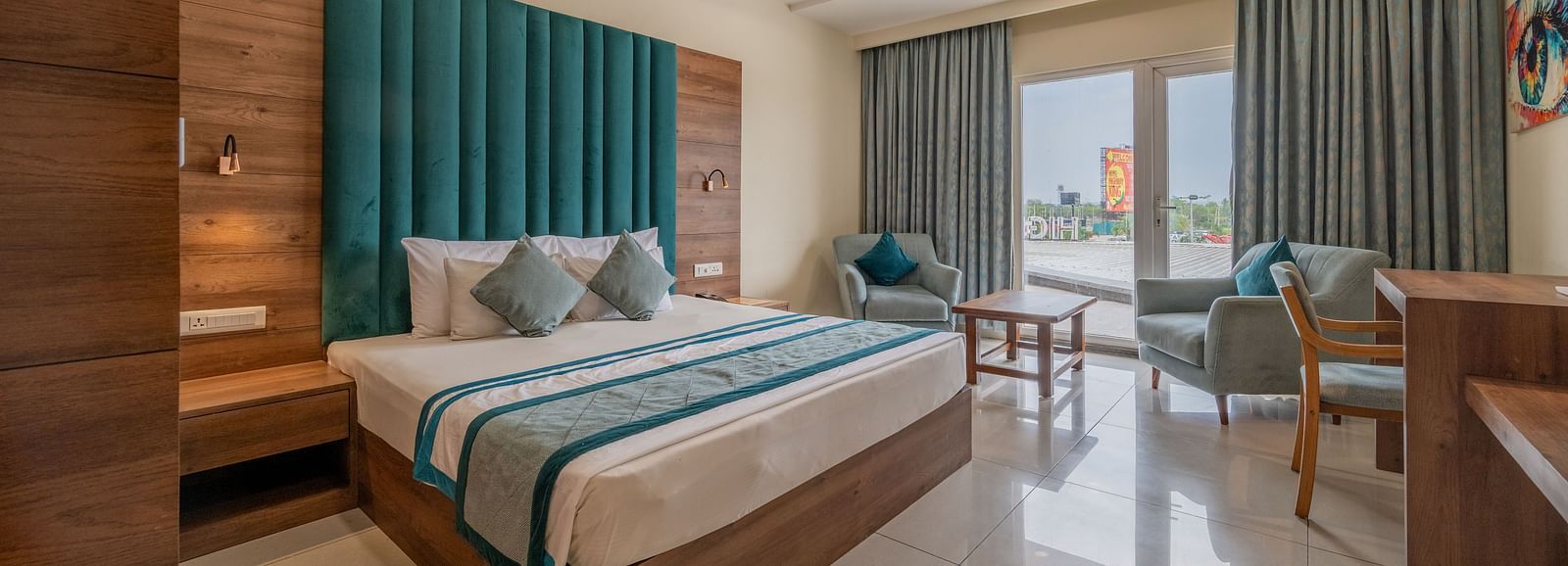 Elegant room with king size bed, full-length curtains, and work station with a seating area nearby at Hotel Highway King, Bilaspur.