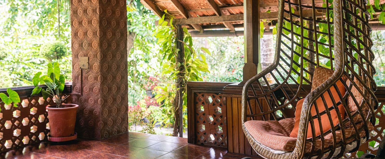 Covered verandah or porch with wooden beams and hanging cane furniture - BluSalzz Collection - Tranquil Resort, Wayanad