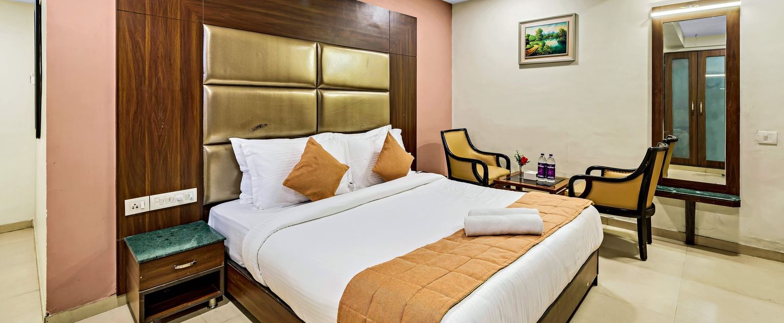A well-lit executive room in Krushnai Resort featuring a double bed with white lnen and yellow runner.