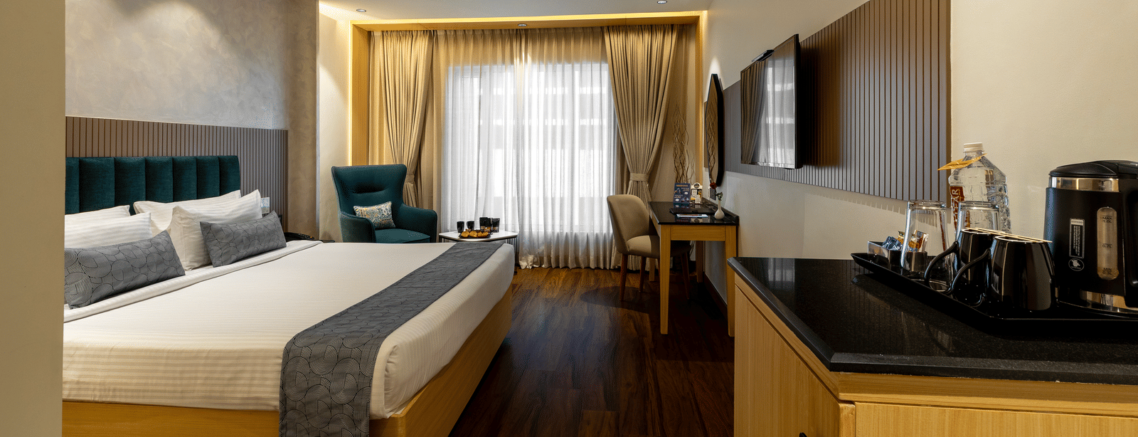 A room at the Citrine Hotel with a king-size bed, a desk, and a window with curtains.