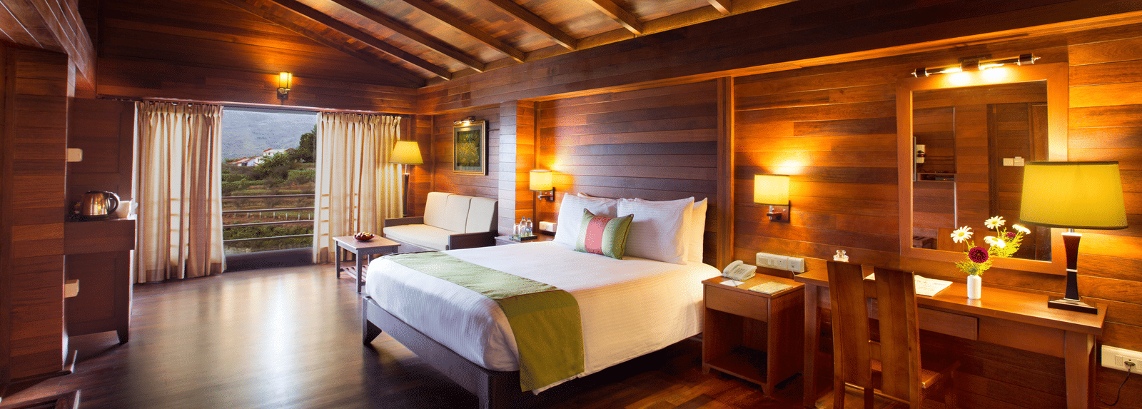 An image of Timber Charlet room with a king size bed, bed side table, lamps, a dressing table, chair, and other decorative items - GReaT Trails Kodaikanal By GRT Hotels