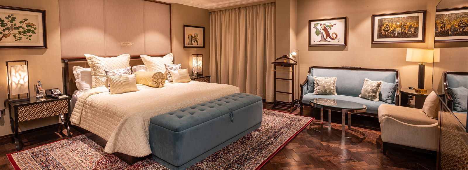 Luxury King Bed Room at The Claridges New Delhi, featuring a cosy king sized bed with plush pillows, bedside lamps, and a sofa seating area in the corner