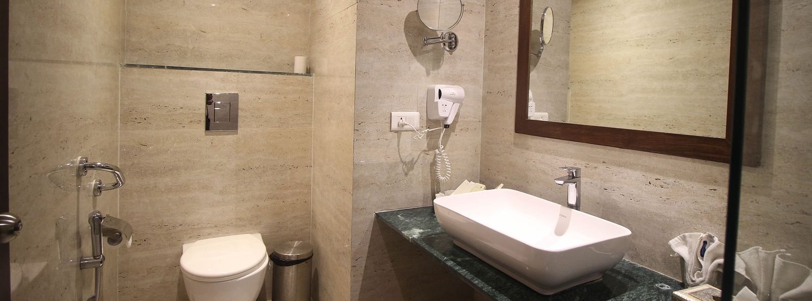 A clean, modern bathroom with a toilet, sink, and mirror. - Bamboo Saa Resort & Spa, Udaipur