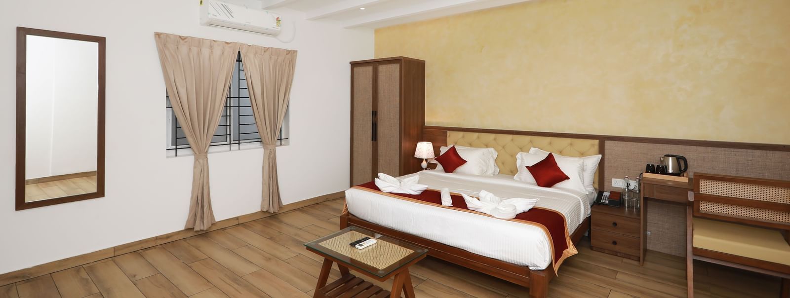 A brightly-lit interior of the Terrace Cottage featuring a double bed along with a wall-mounted mirror at WOW Naturefull Resorts, Yercaud.