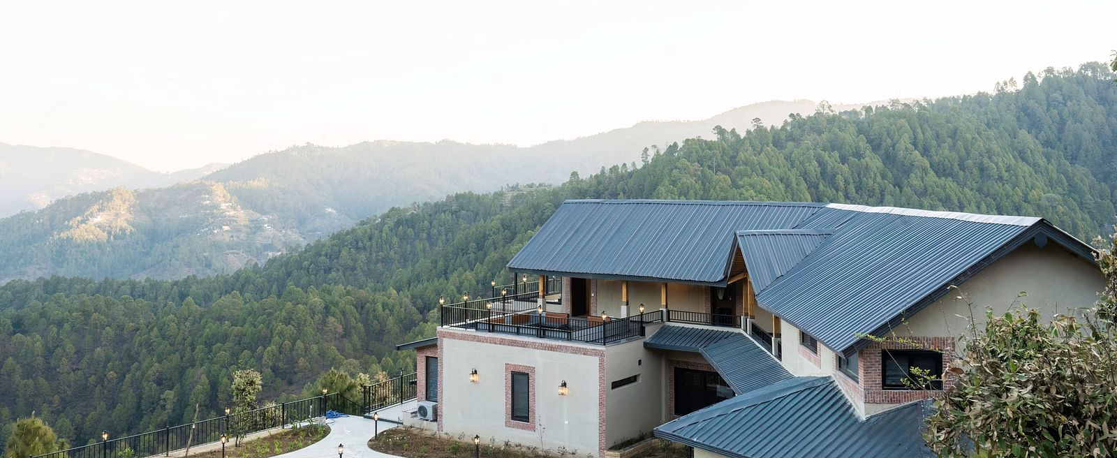 A beautiful exterior of The Chamomile Estate on a hillside with a misty mountain backdrop.
