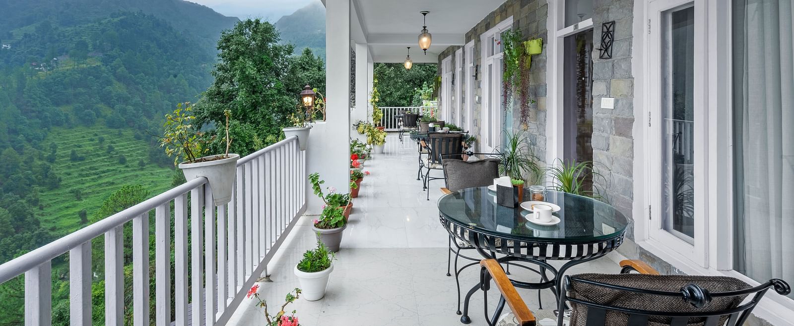 Long verandah with seating arrangements offering panoramic views of the mountains at BluSalzz Collection - Suvaasa Resort, Ramgarh.